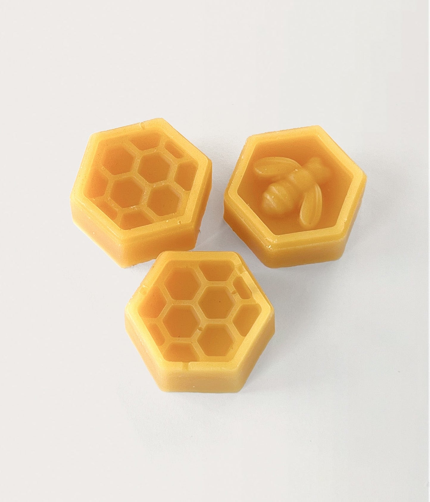 3 stycken gula bivaxbitar med mönster som bi