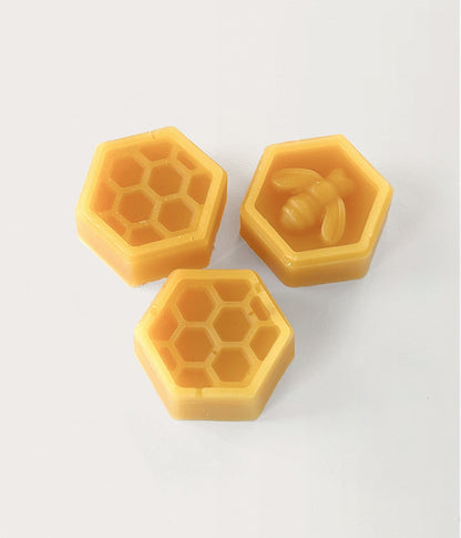 3 stycken gula bivaxbitar med mönster som bi